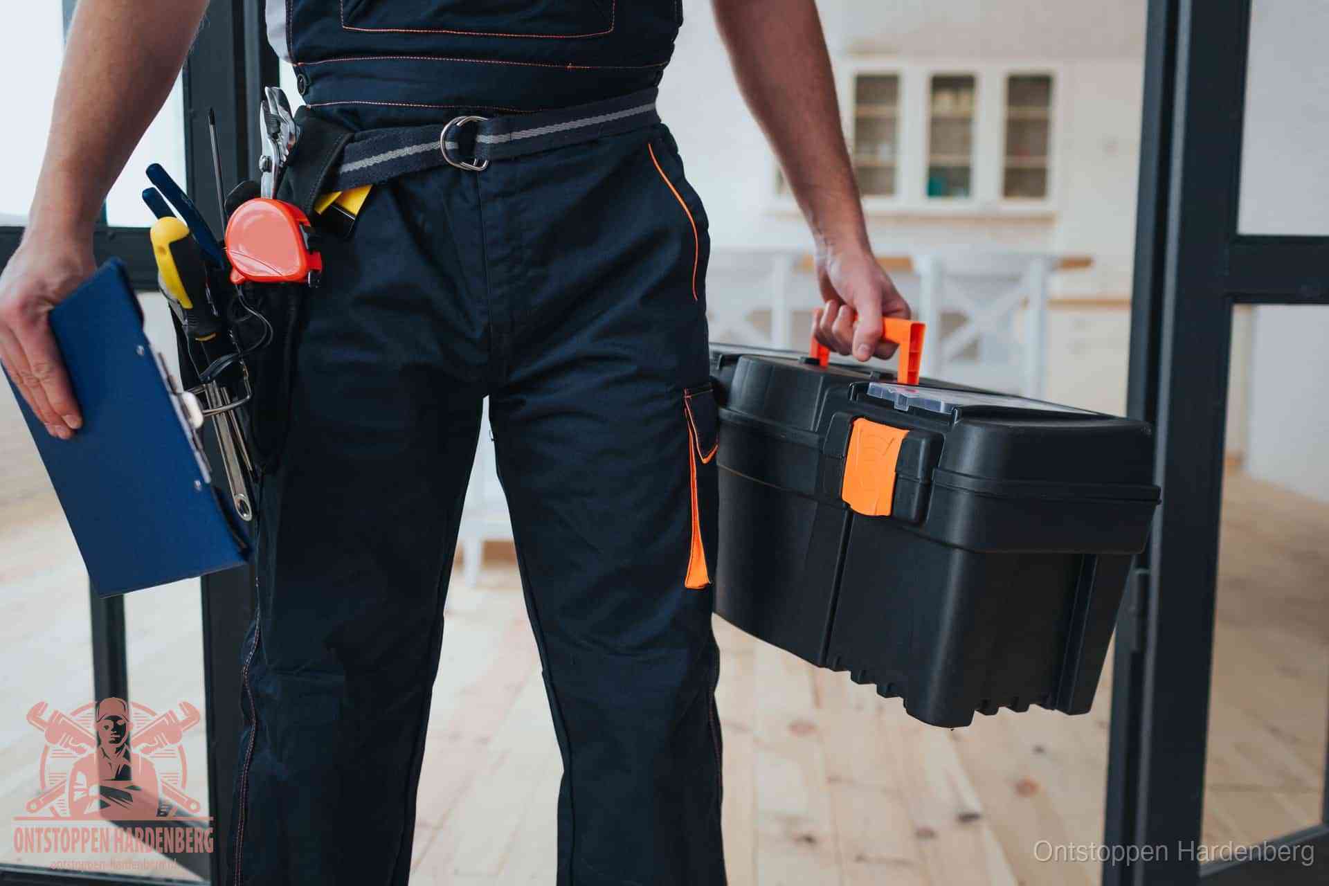 Een monteur met gereedschapsriem en klembord in een keuken, klaar om een transparante prijs voor het gootsteen ontstoppen in Hardenberg te geven