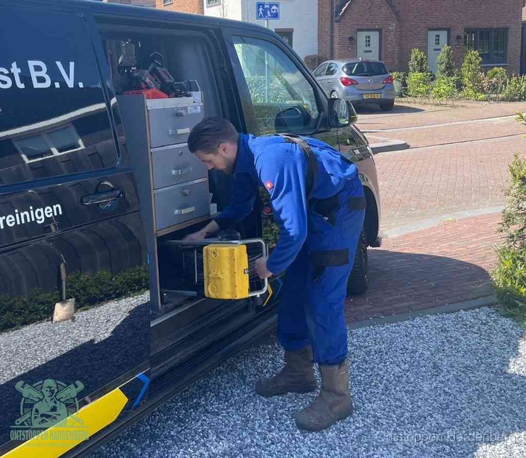 Een monteur pakt buiten op de oprit gereedschap uit de bedrijfsbus, het moment om een professional in te schakelen voor een verstopte afvoer in Hardenberg
