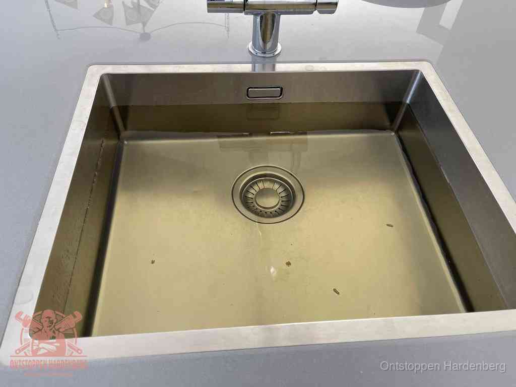 Stilstaand water in een rvs spoelbak dat niet wegloopt, een duidelijk signaal van een gootsteenverstopping in Hardenberg