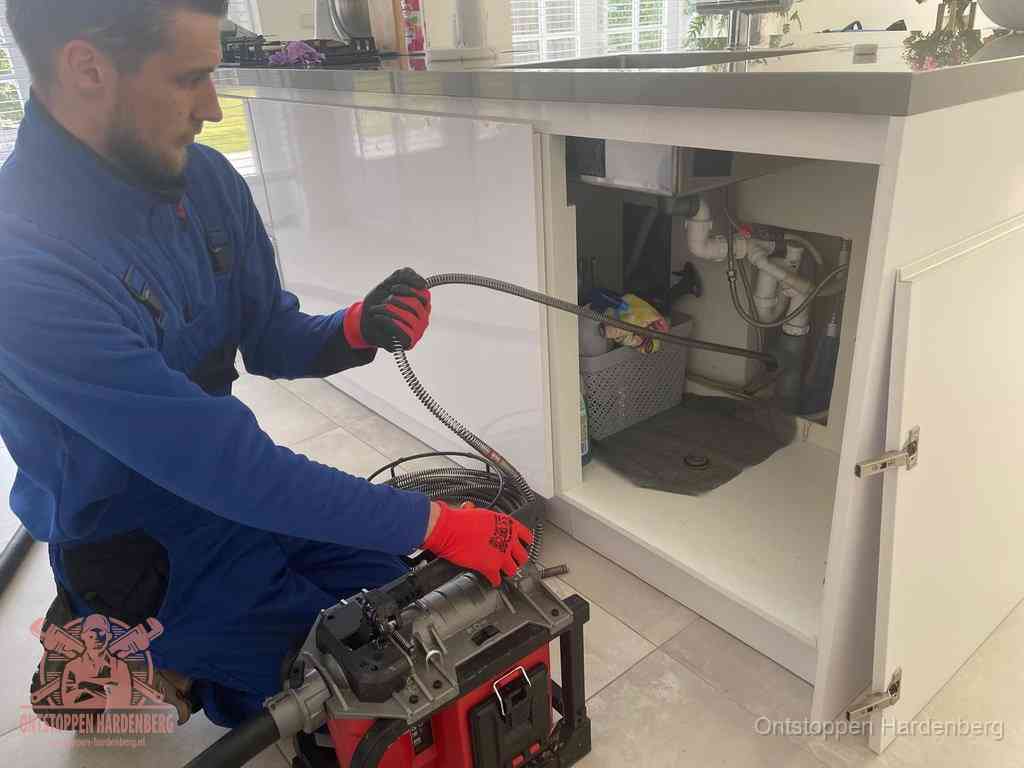 Een monteur reinigt de keukenafvoer grondig met een veermachine om terugkerende gootsteenverstoppingen te voorkomen in Hardenberg