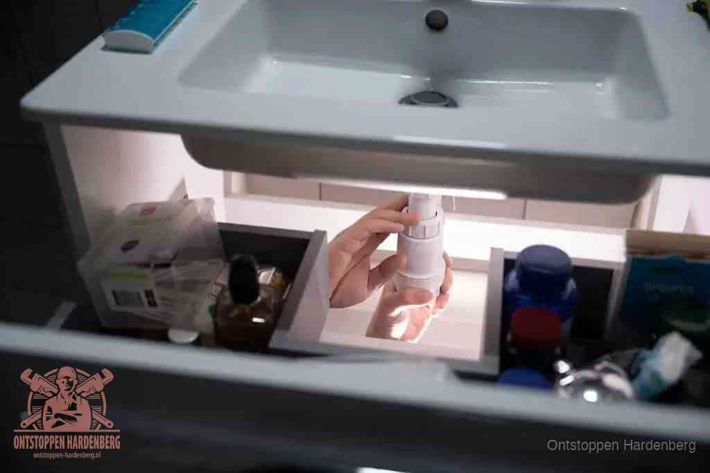 Een pompfles met zeep boven een wastafel in de toiletruimte, de warm water en afwasmiddel-methode om de wc te ontstoppen in Hardenberg