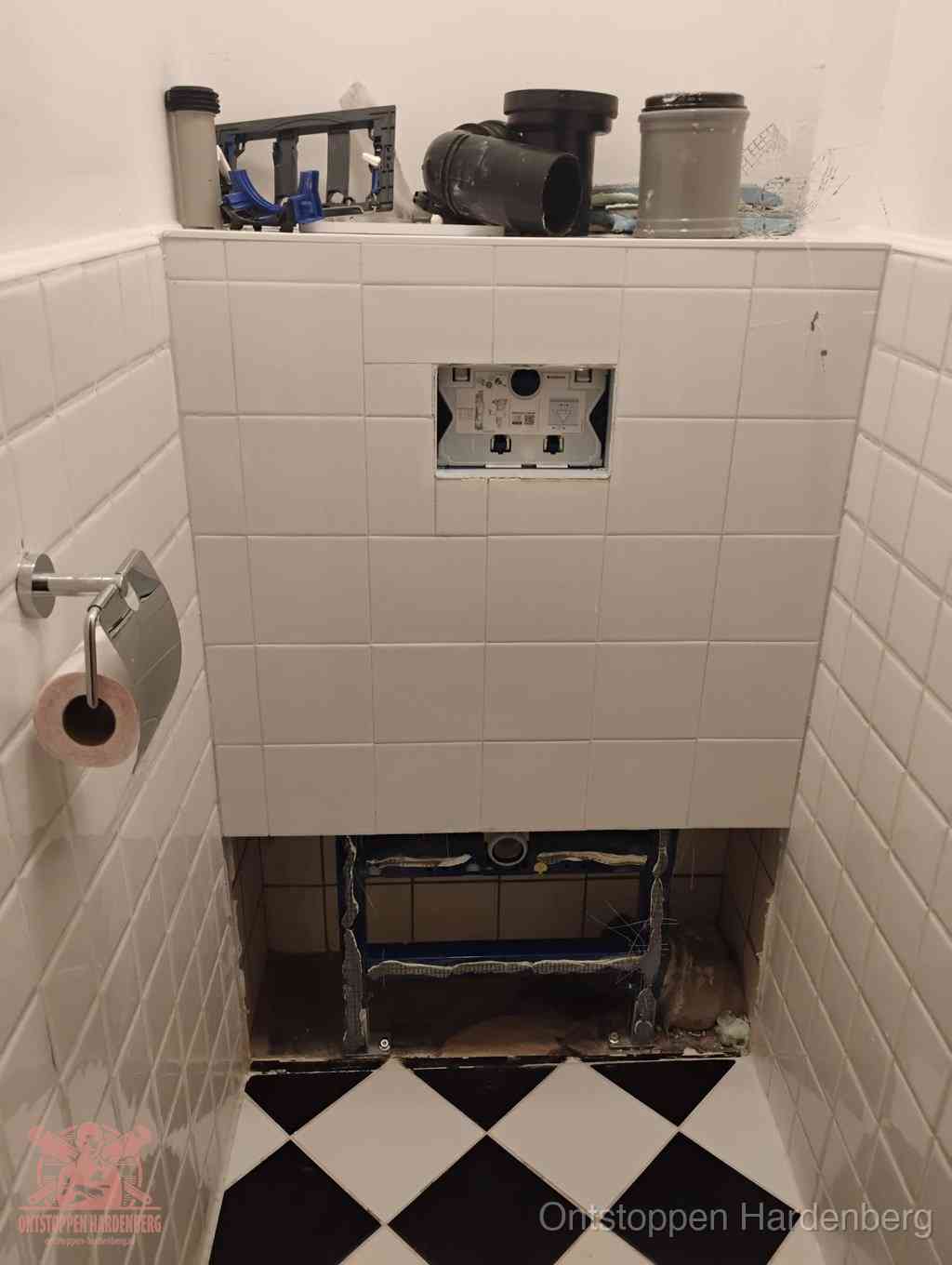 Een toiletruimte waar het hangtoilet en de inbouwreservoir-onderdelen zijn vrijgelegd voor onderhoud, periodiek nazicht voorkomt een wc-verstopping in Hardenberg